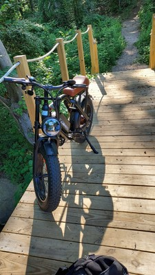 Customer MEGAWHEELS-style fat tire electric bike on a wooden trail bridge